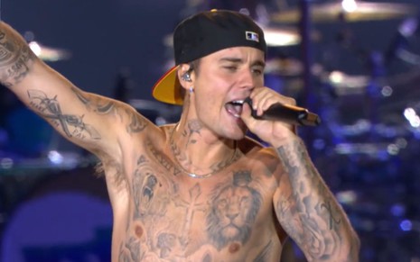 Imagem de Justin Bieber sem camisa e de boné preto durante show no Rock in Rio