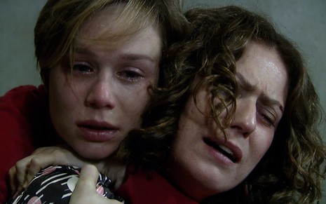 As atrizes Mariana Ximenes e Patricia Pillar como Lara e Flora em A Favorita; elas estão abraçadas e e sentadas, com cara de choro