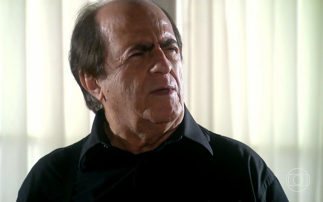 O ator Ary Fontoura como Silveirinha em A Favorita; ele está olhando para o lado com os olhos quase fechados e cara de dúvida