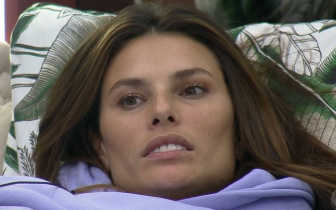 Dayane está deitada, olha para cima e veste blusa roxa