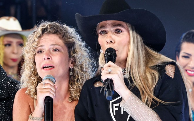 Bárbara Borges e Adriane Galisteu falando ao microfone no palco da final de A Fazenda 14, da Record