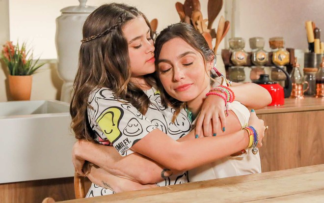 Julieta (Vittória Seixas) abraça Mariana (Juliana Schalch) em cena da novela