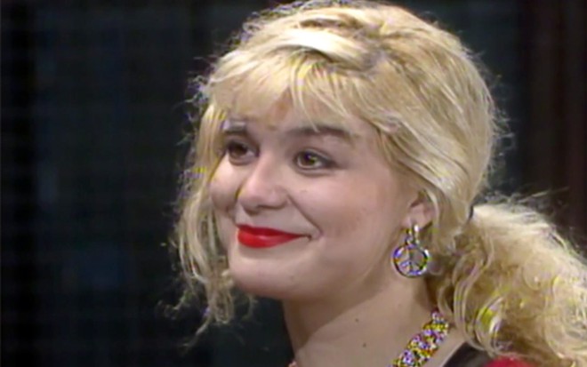 A atriz Chris Pitsch em A Viagem (1994), sorrindo de boca fechada, com fundo preto