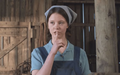 Mia Goth leva o dedo à boca como se pedisse silêncio em cena do filme Pearl
