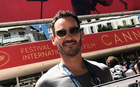 Aaron Salles Torres segura um jornal em frente a entrada do Festival de Cannes