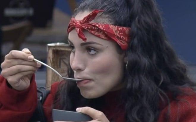 Imagem de Aline Mineiro de bandana vermelha comendo em A Fazenda 13