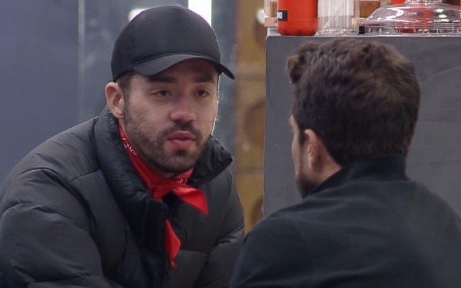 Imagem de Rico Melquiades usando boné durante conversa com Erasmo Viana
