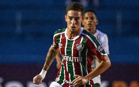 Agner, do Fluminense, em campo com uniforme listrado em grená, verde e branco