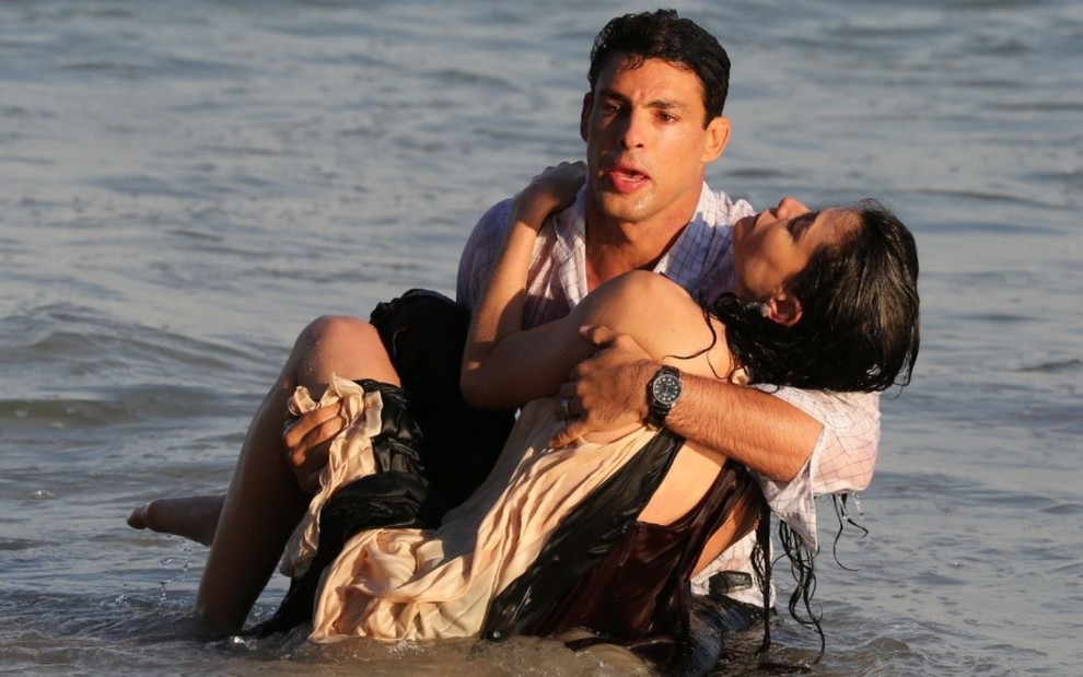 Bárbara (Alinne Moraes) é carregada por Christian (Cauã Reymond) no mar em Um Lugar ao Sol