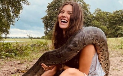 Alanis Guillen sorri com uma cobra durante as gravações durante as gravações de Pantanal