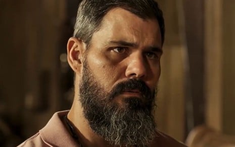 Juliano Cazarré com expressão séria em cena como Alcides na novela Pantanal