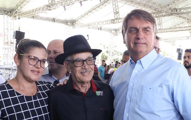 Alcino Lima usa chapéu e camisa na cor preta e esta entra a namorada, Giovanete Fontes, com vestido quadriculado, e Bolsonaro com camisa branca