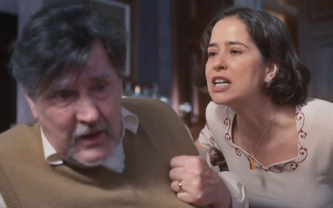Matias (Antonio Calloni) está encolhido enquanto Heloísa (Paloma Duarte) o enfrenta em cena da novela Além da Ilusão