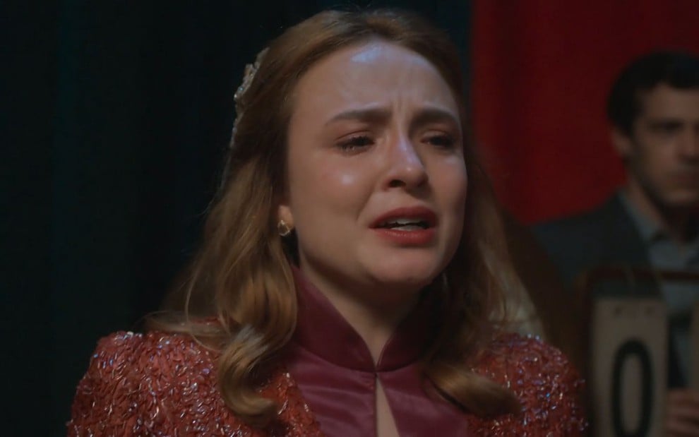 A atriz Larissa Manoela como Isadora em Além da Ilusão; ela está olhando para o lado e chorando
