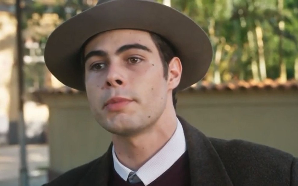 Davi/Rafael (Rafael Vitti) em cena de Além da Ilusão; ele usa chapéu e trajes escuros, com gola branca
