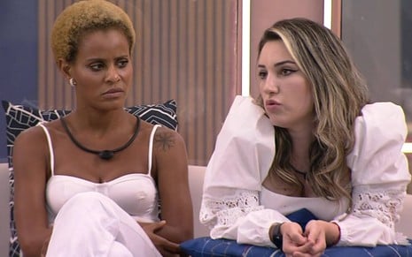 Foto mostra Aline Wirley sentada ao lado de Amanda Meirelles