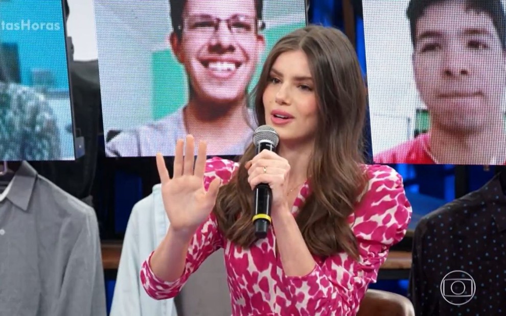 No estúdio do programa Altas Horas, atriz Camila Queiroz veste roupa com dois tons de rosa e faz sinal de pare com as mãos