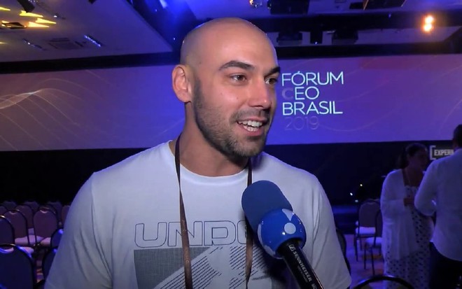 Amilcare Dallevo Neto com uma camisa branca, dando entrevista para a RedeTV!, em um Fórum realizado em 2019