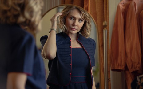 Elizabeth Olsen mexe no cabelo enquanto olha no espelho em cena de Amor e Morte