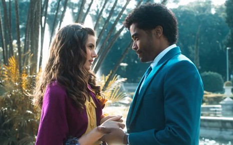 Os atores Camila Queiroz e Diogo Almeida frente a frente, de mãos dadas, em cena externa de Amor Perfeito
