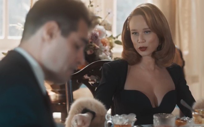 Gilda (Mariana Ximenes) e Gaspar (Thiago Lacerda) em mesa de café da manhã, ela de vestido preto de frente, ele de lado, em cena da novela Amor Perfeito, da Globo