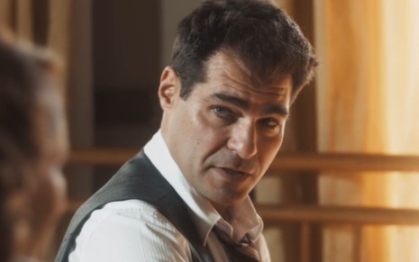 O ator Thiago Lacerda em cena como Gaspar em Amor Perfeito, com olhar sério, expressão questionadora, de camisa e colete