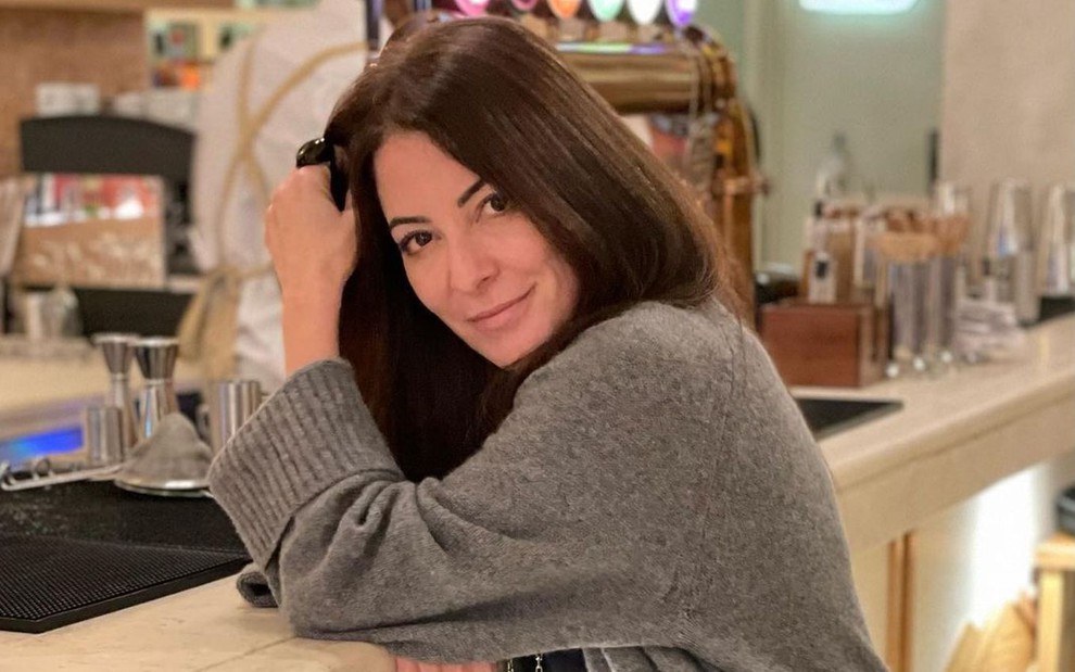De suéter cinza, Ana Paula Padrão se apoia em um balcão de bar em foto de seu Instagram