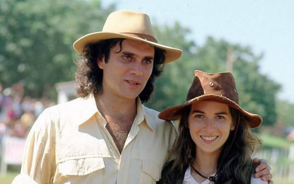 Os atores Almir Sater e Ingra Lyberato lado a lado, ambos com chapéus de cowboy, ela sorrindo, em gravação de A História de Ana Raio e Zé Trovão