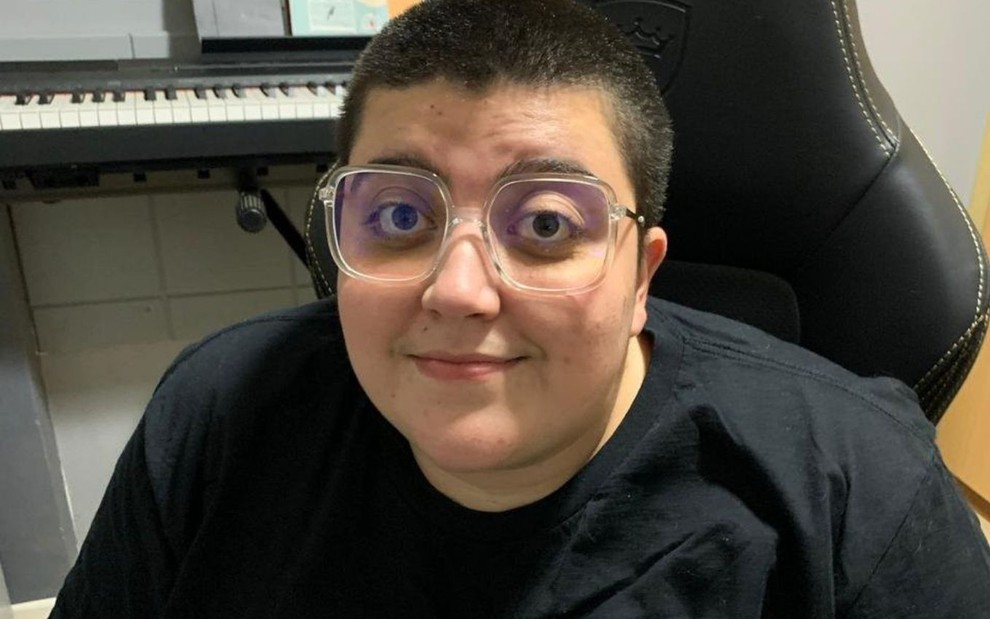 Ana Vilela veste preto, usa óculos e está sentada em escritório