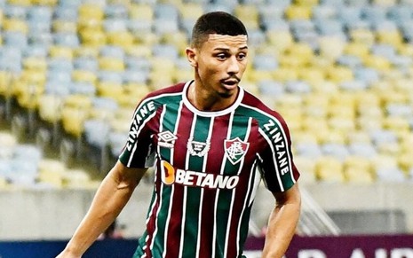 André, do Fluminense, joga pelo clube com uniforme com listras verde, branco e vinho