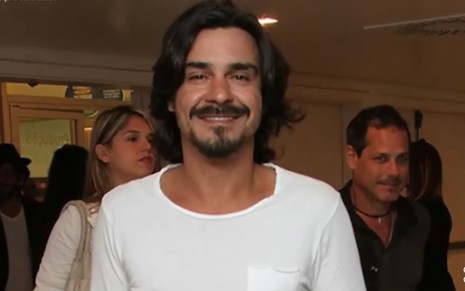 O ator André Gonçalves sorri para foto, com camiseta branca