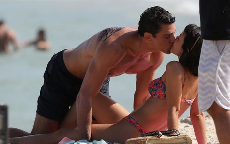 Cauã Reymond e Andréia Horta se beijam deitados na praia de Grumari, no Rio de Janeiro