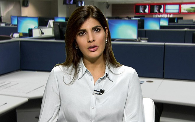 Andréia Sadi com uma camisa branca e falando diretamente da redação da Globo em Brasília