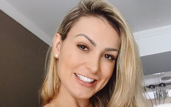 Andressa Urach loira, cabelo liso, sorridente, com marca de biquíni à mostra, em foto do pescoço para cima