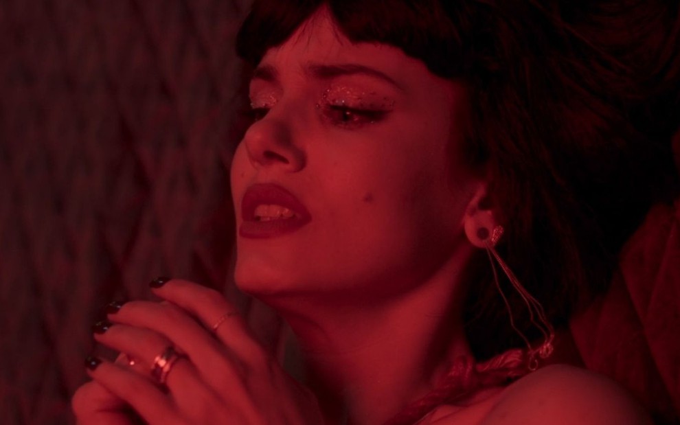 Com cara de sofrimento, Angel (Camila Queiroz) está deitada e com as mãos amarradas em cena da novela Verdades Secretas 2