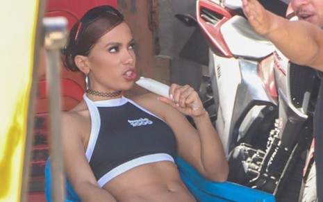Anitta chupando um gelinho durante a gravação de um videoclipe nas ruas da comunidade da Tijuquinha