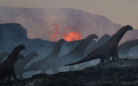 Isissauros passam na frente de um vulcão em erupção em imagem feita por computador