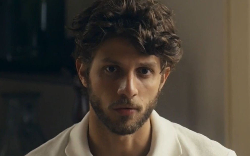 Chay Suede com expressão séria em cena como Ari na novela Travessia