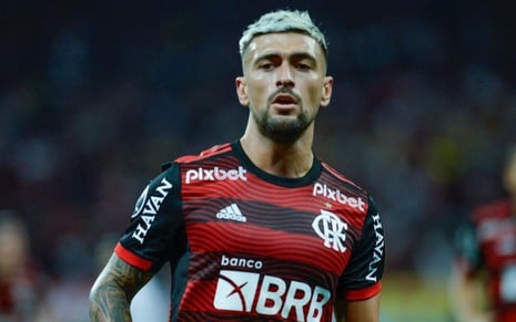 Arrascaeta, do Flamengo, em campo pelo clube com uniforme listrado vermelho e preto