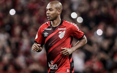 Fernandinho, do Athletico Paranaense, caminha em campo e veste uniforme vermelho e preto