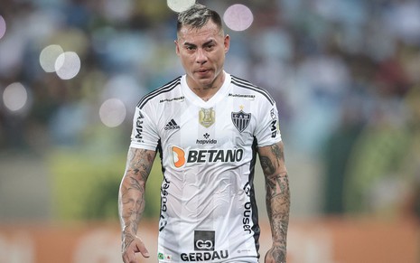 Vargas, do Atlético Mineiro, caminha em campo e veste uniforme branco com detalhes pretos