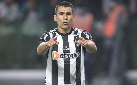 Junior Alonso, do Atlético Mineiro, aponta para a câmera e veste uniforme listrado em branco e preto
