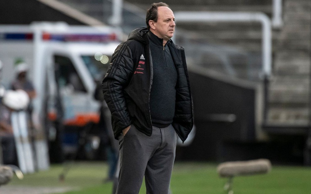 De blusa preta do Flamengo, Rogério Ceni observa a equipe na beira do gramado em jogo do Brasileirão