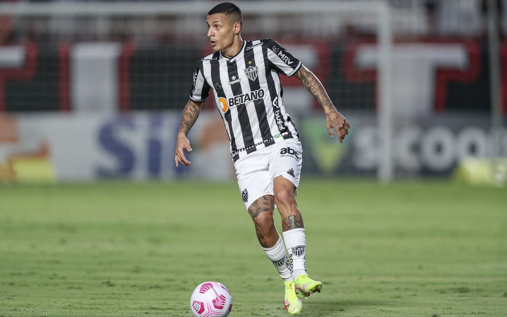 Jogador Guilherme Arana, do Atlético Mineiro, vestindo uniforme branco e preto, dominando a bola em partida