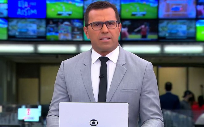 Rodrigo Bocardi de blazer cinza no comando do Jornal Hoje, da Globo, de sábado (6)