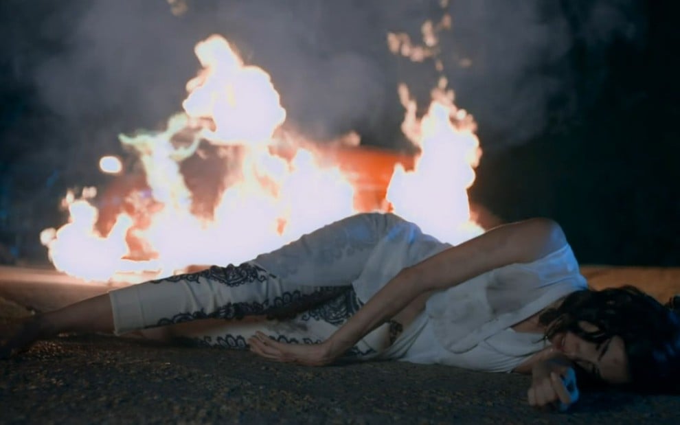 Imagem de Paola, interpretada por Sandra Echeverria, desmaiada na frente de um carro em chamas em A Usurpadora