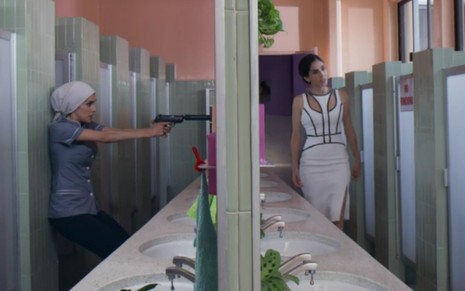 Imagem de Sandra Echeverria como Paola, apontando uma arma para Paulina, também interpretada por Sandra, no remake de A Usurpadora