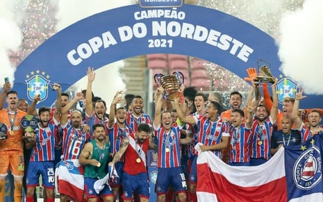 Time do Bahia, com camisa tricolor clássica, sorrindo e levantando o troféu de campeão da Copa do Nordeste 2021: Disney quer exibir a competição em 2022