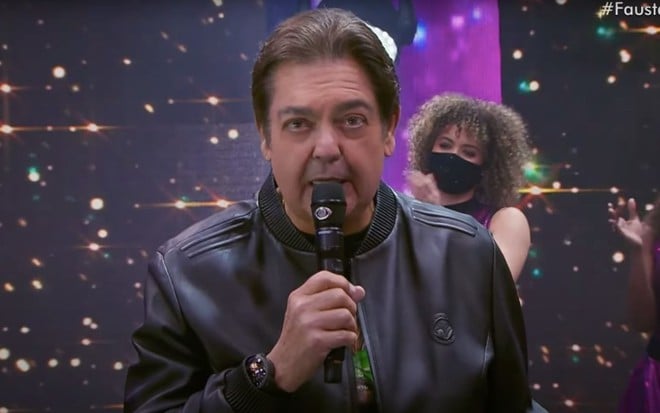 O apresentador Fausto Silva segura microfone no palco do Faustão na Band