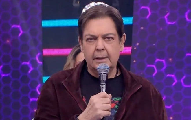 Faustão com camisa marrom no cenário do Faustão na Band